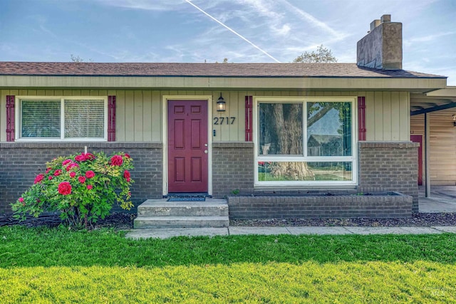property entrance with a yard, brick siding, and a chimney