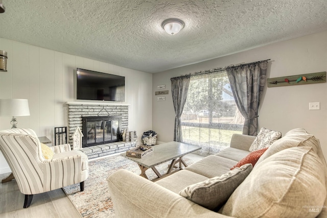 living room featuring a fireplace, a textured ceiling, and wood finished floors