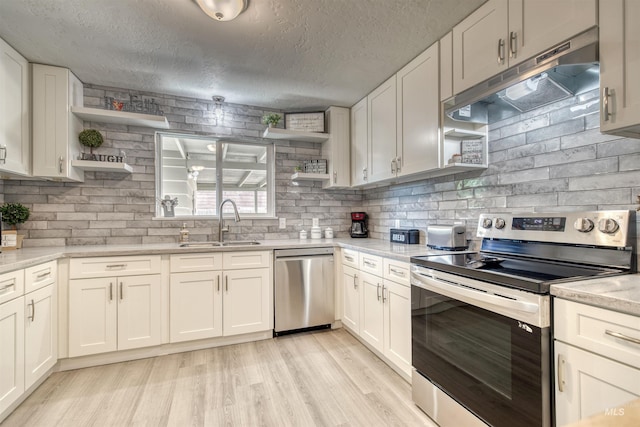 kitchen featuring under cabinet range hood, open shelves, a sink, and appliances with stainless steel finishes