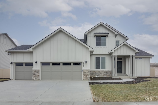 view of front of home featuring driveway, board and batten siding, a shingled roof, an attached garage, and a front lawn