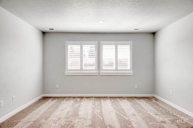 empty room featuring baseboards, a textured ceiling, and carpet