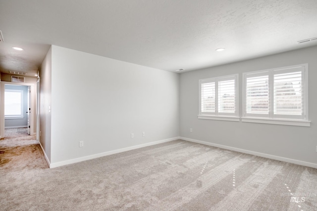 spare room with baseboards, light carpet, and plenty of natural light