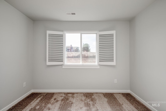 carpeted spare room with visible vents and baseboards