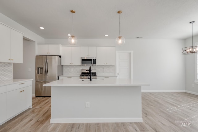 kitchen featuring tasteful backsplash, white cabinets, a sink, appliances with stainless steel finishes, and light countertops