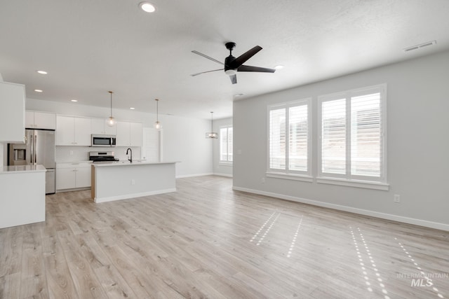 unfurnished living room featuring recessed lighting, light wood-style flooring, ceiling fan, baseboards, and visible vents