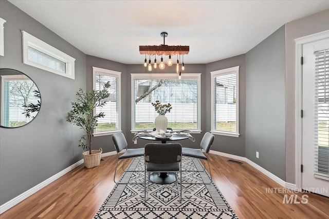 dining space with light wood finished floors, an inviting chandelier, visible vents, and baseboards