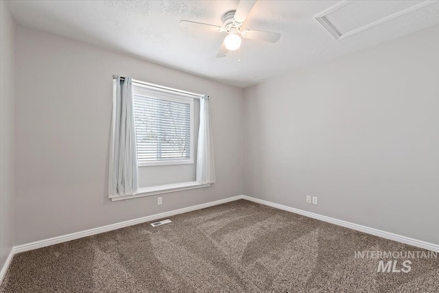 unfurnished room with visible vents, attic access, carpet flooring, ceiling fan, and baseboards