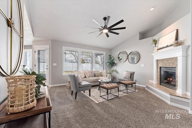 carpeted living area with a ceiling fan, a high end fireplace, lofted ceiling, and baseboards