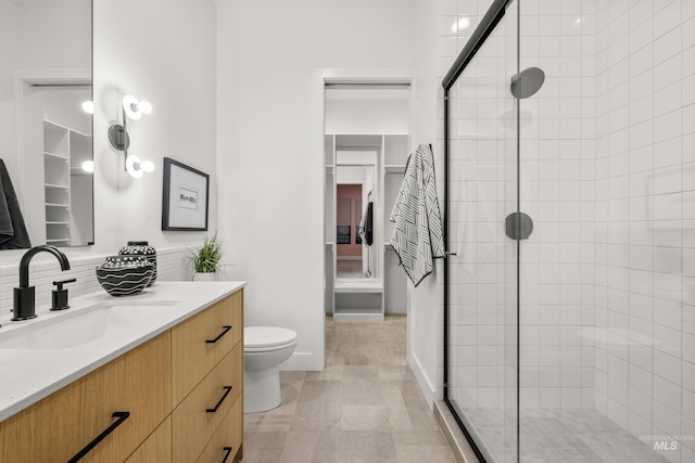 bathroom featuring vanity, toilet, a shower with shower door, and backsplash