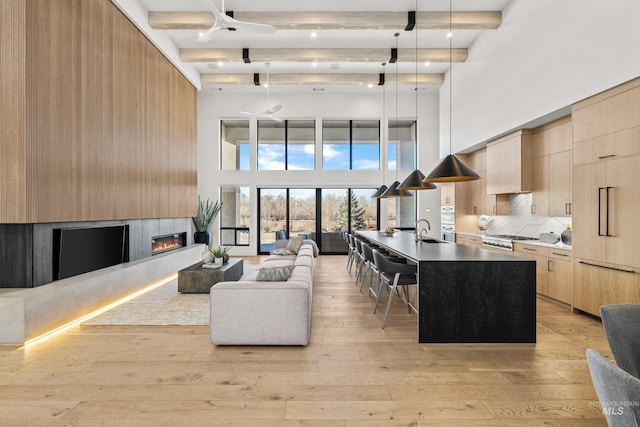 living room with sink, light hardwood / wood-style floors, beamed ceiling, and ceiling fan