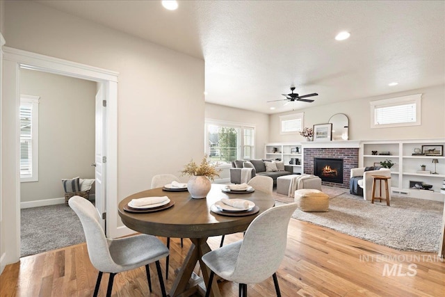 dining area with a fireplace, recessed lighting, a ceiling fan, a textured ceiling, and wood finished floors