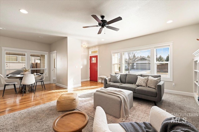 living area with a textured ceiling, recessed lighting, light wood-style flooring, and baseboards