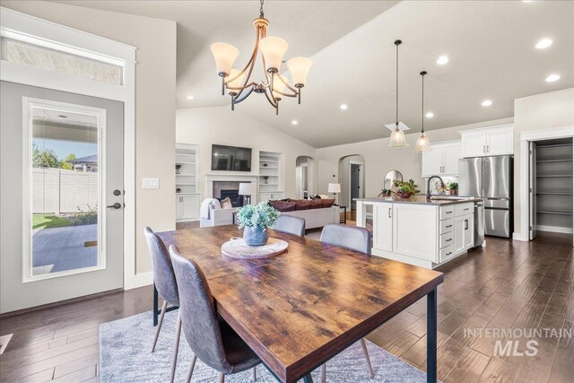 495 W Tall Prairie Dr, Meridian, ID 83642 - dining area featuring arched walkways, dark wood-type flooring, lofted ceiling, built in features, and a chandelier