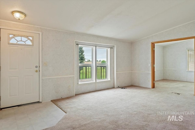 foyer entrance featuring lofted ceiling, carpet, and plenty of natural light