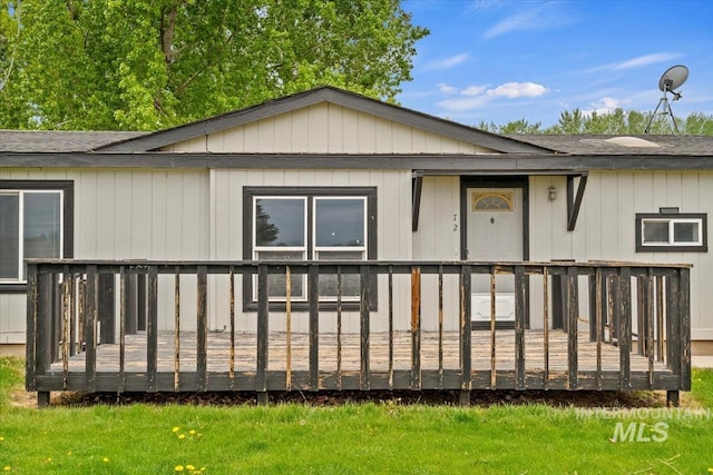 back of property featuring a shingled roof, a yard, and a deck