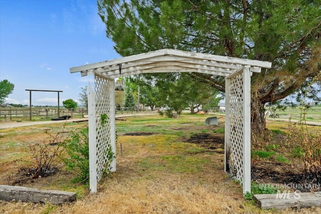 view of yard featuring a detached carport, fence, and a rural view