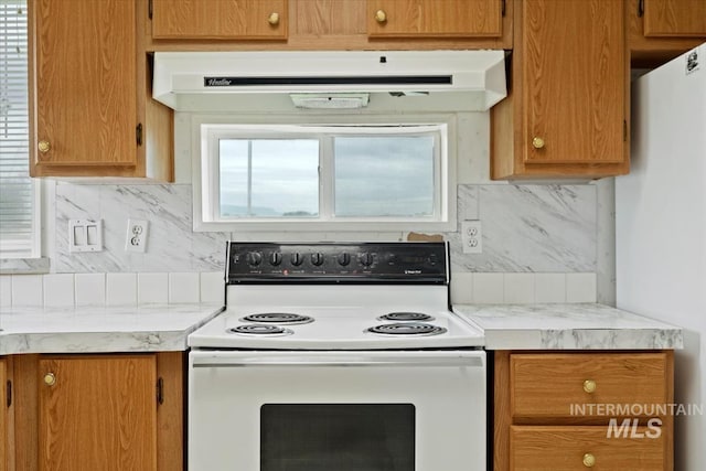 kitchen featuring backsplash, white appliances, light countertops, and under cabinet range hood