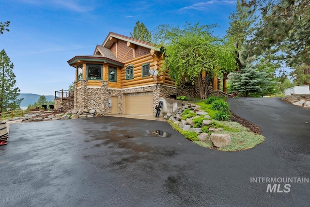 1533 Pine Lakes Ranch Dr, Cascade, ID 83611 - cabin with stone siding, driveway, an attached garage, and log exterior