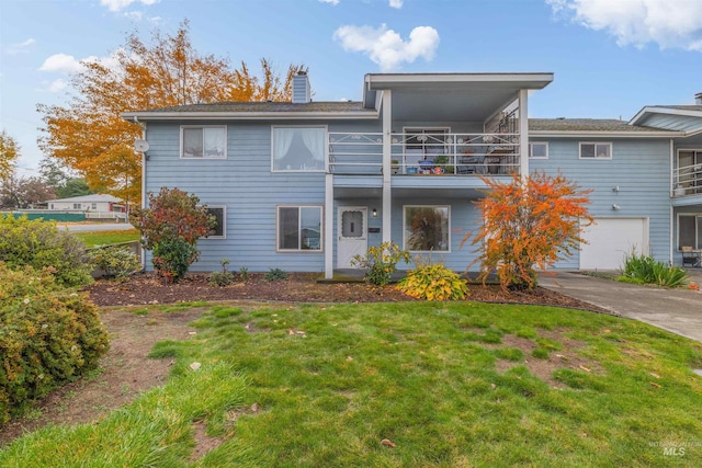 view of front of property with driveway, a garage, a balcony, a chimney, and a front lawn