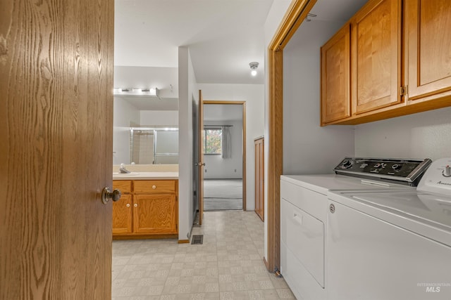 clothes washing area with separate washer and dryer, a sink, visible vents, cabinet space, and light floors