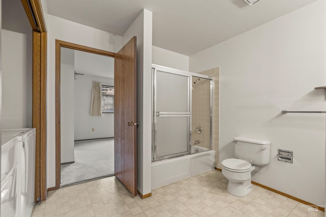 bathroom featuring combined bath / shower with glass door, tile patterned floors, toilet, and washer and dryer