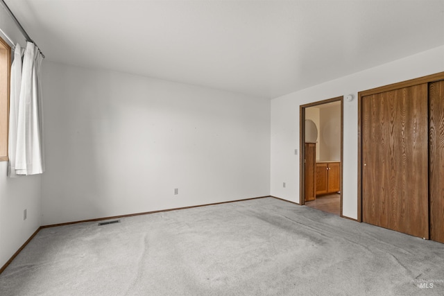 unfurnished bedroom with carpet flooring, visible vents, baseboards, and ensuite bathroom