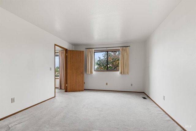 unfurnished room with light carpet, visible vents, and baseboards