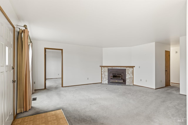 unfurnished living room featuring carpet, a fireplace with flush hearth, and baseboards