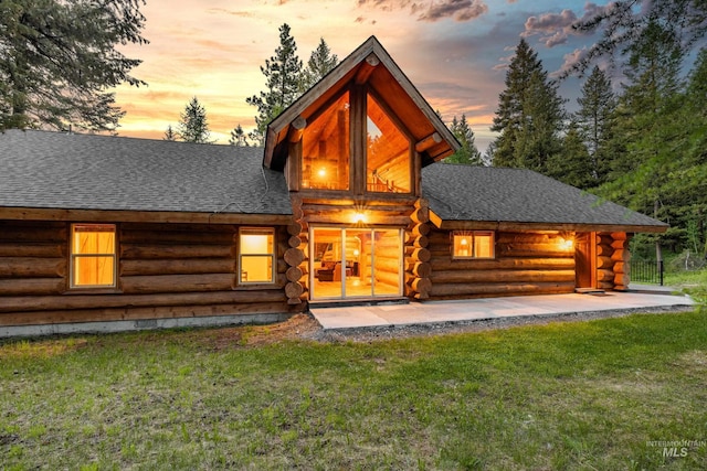 881 Sheila, Mccall, ID 83638 - back of house at dusk featuring log exterior, roof with shingles, and a lawn