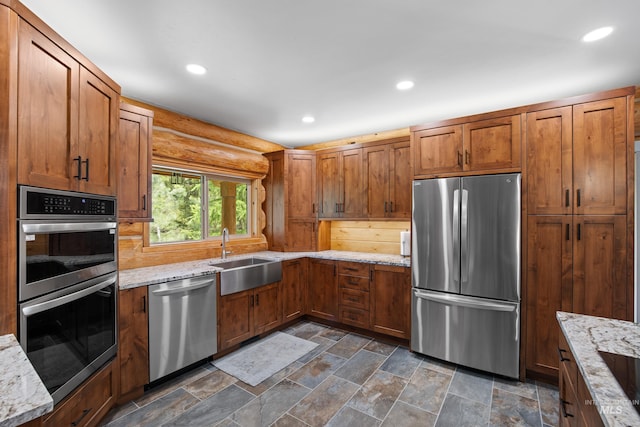 881 Sheila, Mccall, ID 83638 - kitchen featuring stainless steel appliances, brown cabinetry, light stone countertops, rustic walls, and recessed lighting