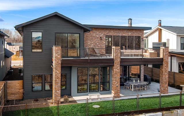 rear view of house with a fenced backyard, brick siding, a balcony, and a patio area