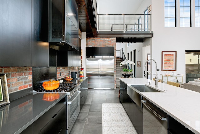 kitchen featuring a sink, premium appliances, modern cabinets, and dark cabinets