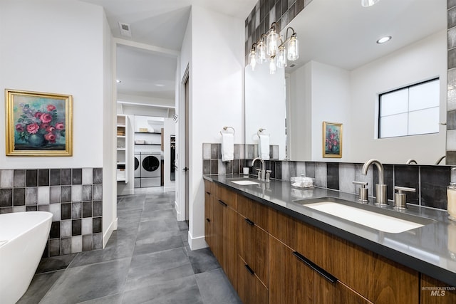 bathroom with washing machine and clothes dryer, visible vents, a spacious closet, and a sink