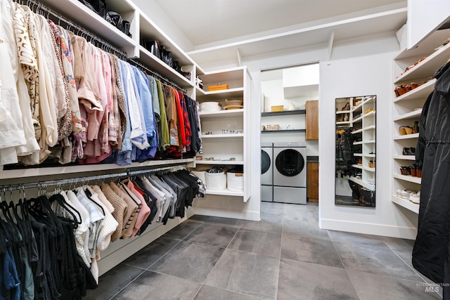 walk in closet with washer and dryer and dark tile patterned flooring