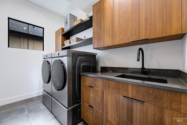 clothes washing area featuring cabinet space, washing machine and dryer, baseboards, and a sink