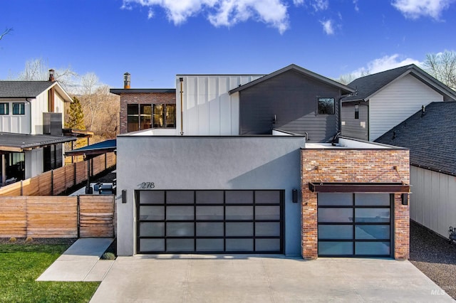 contemporary house with brick siding, stucco siding, driveway, and fence