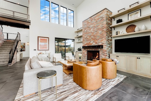 living area with stairway, a fireplace, and a towering ceiling