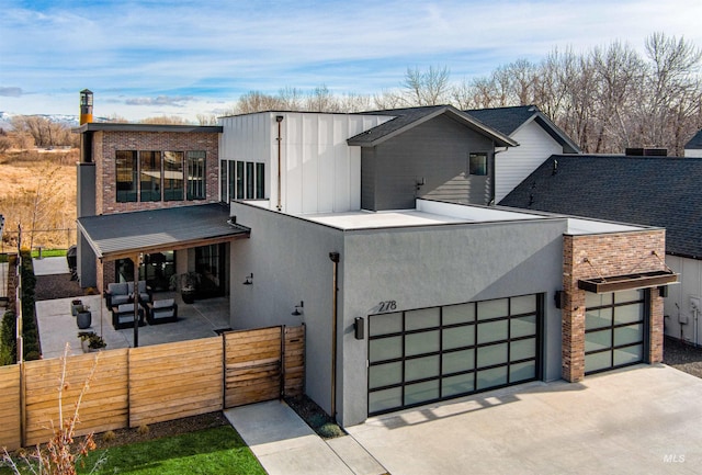 contemporary home featuring stucco siding, concrete driveway, a garage, fence private yard, and a patio area