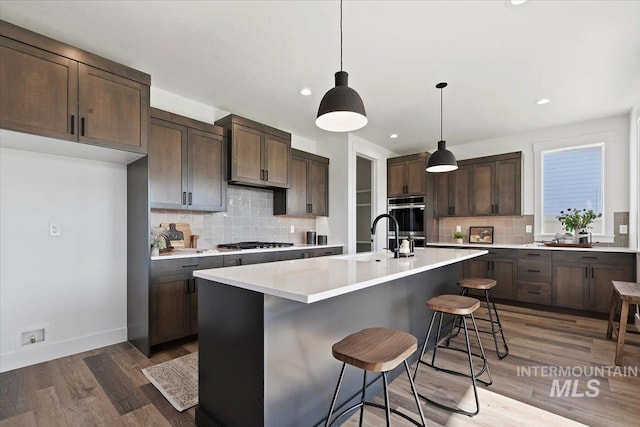 2394 E Monhegan Dr, Eagle, ID 83616 - kitchen with tasteful backsplash, appliances with stainless steel finishes, dark brown cabinets, light countertops, and recessed lighting
