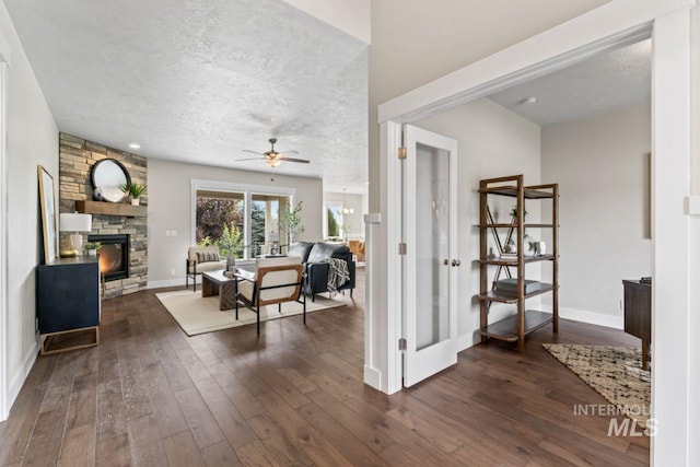12462 S Sunrise Mist Loop, Nampa, ID 83686 - living room featuring a fireplace, dark wood finished floors, ceiling fan, and a textured ceiling