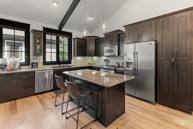 1520 Roosevelt Ave, Mccall, ID 83638 - kitchen featuring appliances with stainless steel finishes, a sink, light stone counters, decorative backsplash, and a kitchen bar