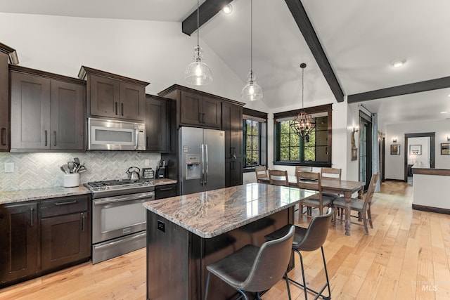 1520 Roosevelt Ave, Mccall, ID 83638 - kitchen featuring appliances with stainless steel finishes, beam ceiling, a chandelier, decorative backsplash, and light stone counters