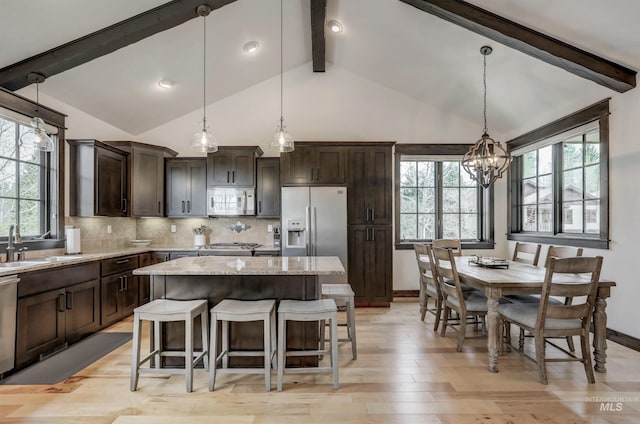1520 Roosevelt Ave, Mccall, ID 83638 - kitchen with stainless steel appliances, dark brown cabinets, light stone countertops, a chandelier, and plenty of natural light