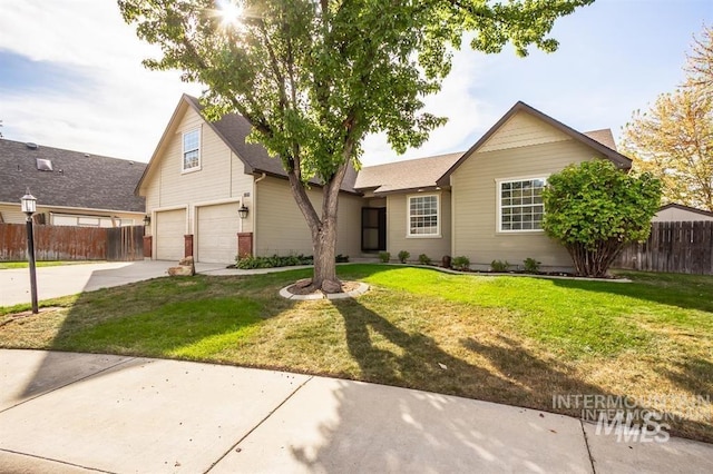 view of front of property with concrete driveway, a front lawn, and fence