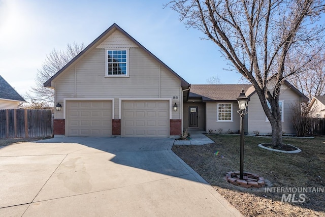 traditional home with fence, concrete driveway, and brick siding