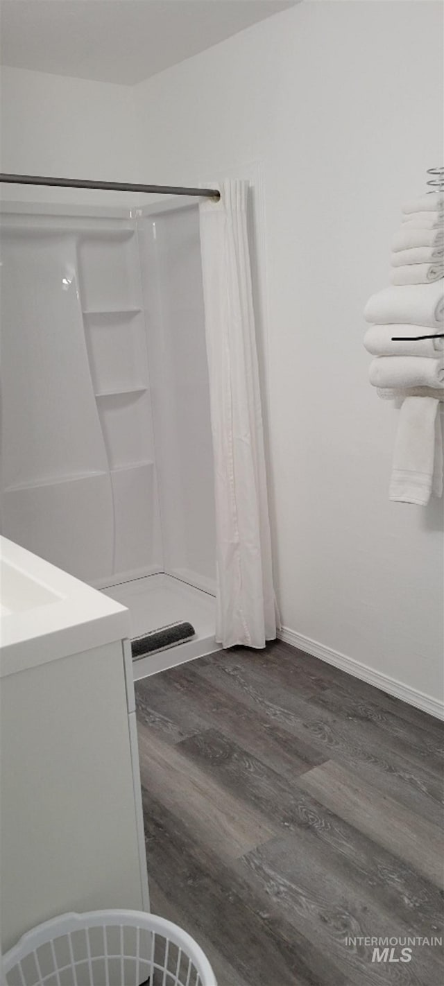 bathroom with wood-type flooring, a shower with curtain, and vanity