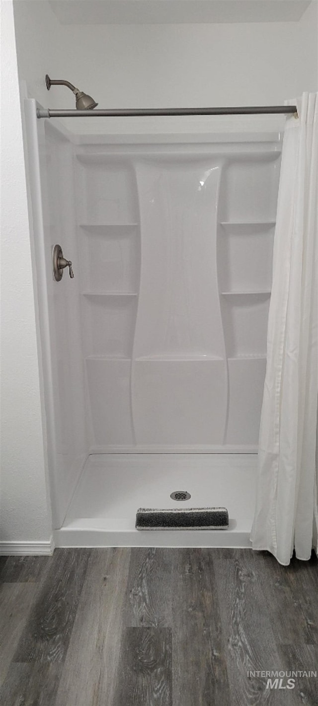 bathroom with a shower with shower curtain and wood-type flooring