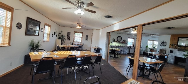 dining space with ceiling fan, a textured ceiling, dark hardwood / wood-style floors, and crown molding