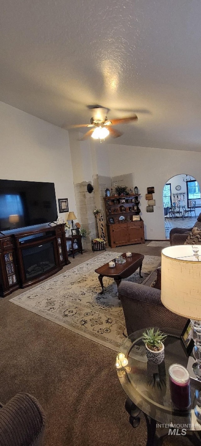 carpeted living room featuring ceiling fan and a textured ceiling