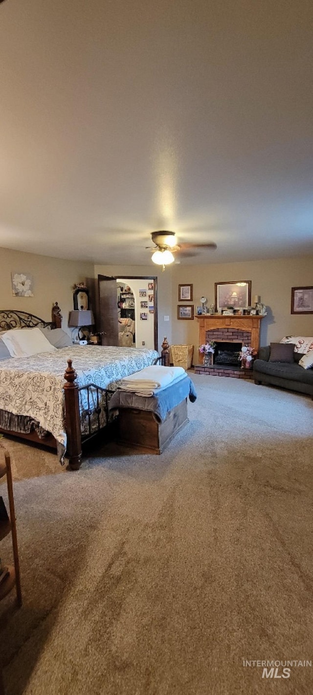 carpeted bedroom with a fireplace and ceiling fan